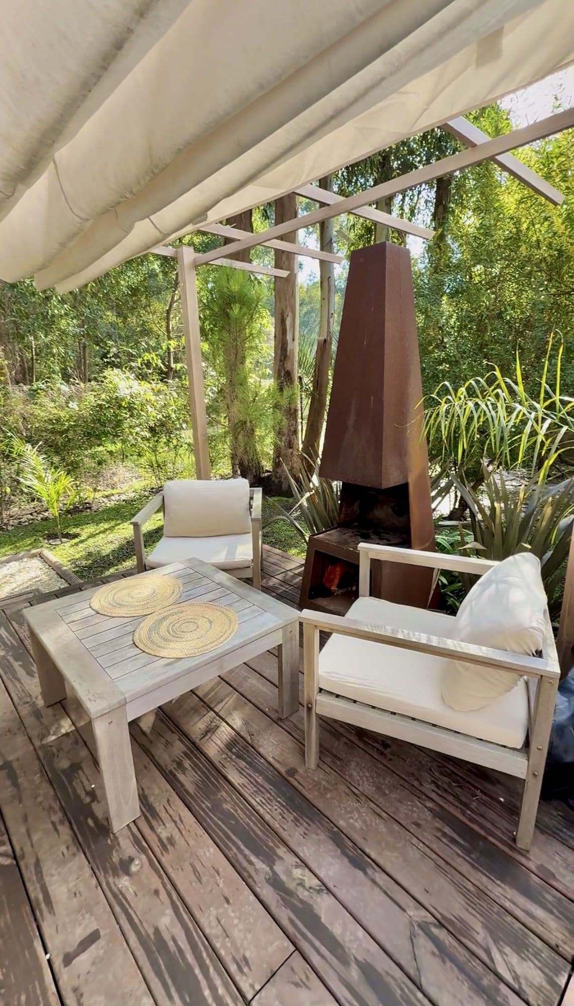 Deck de BondiHouse con living exterior, pérgola y estufa de acero corten