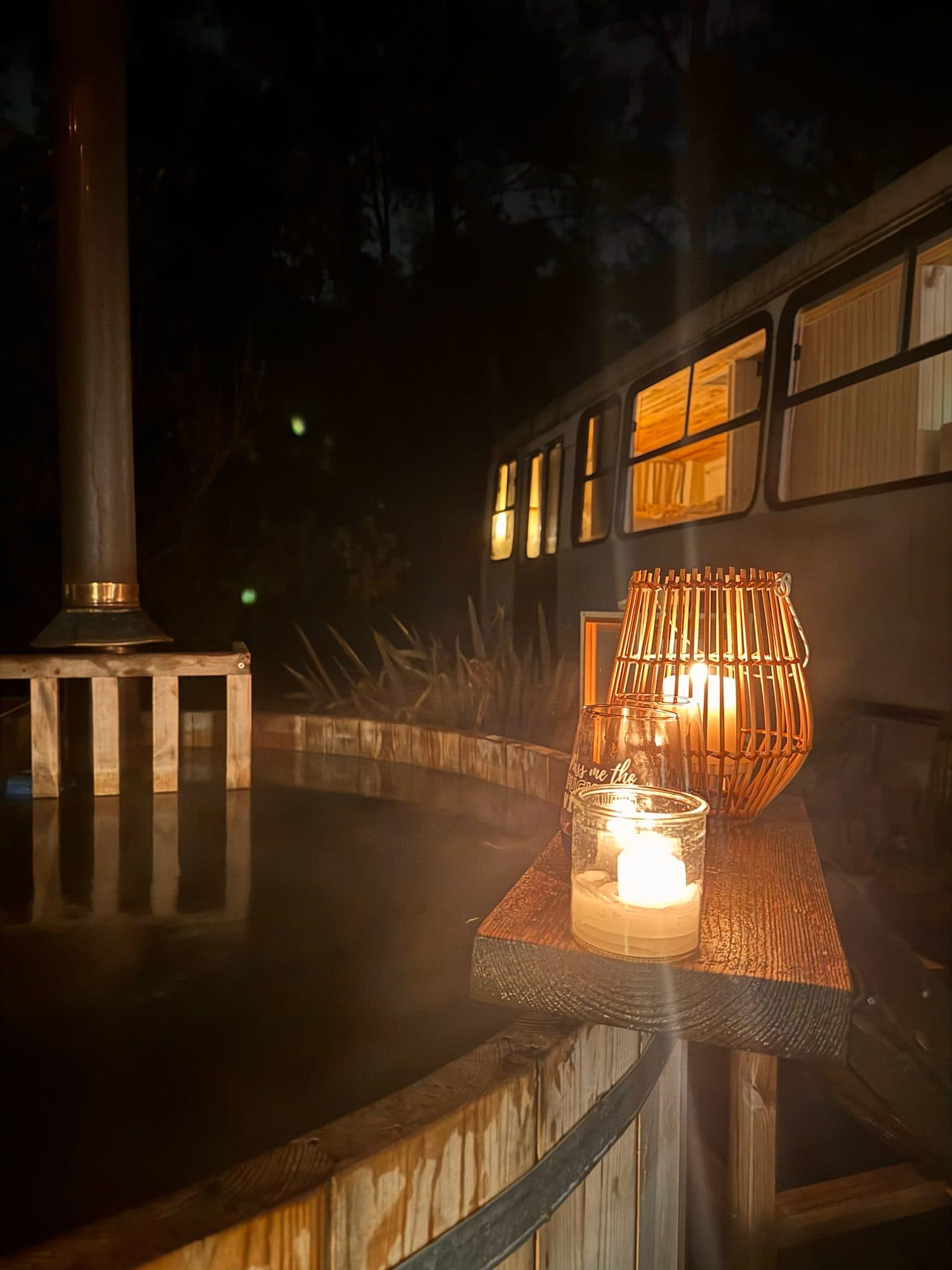La tina a leña de noche con un farol y una vela encendidos