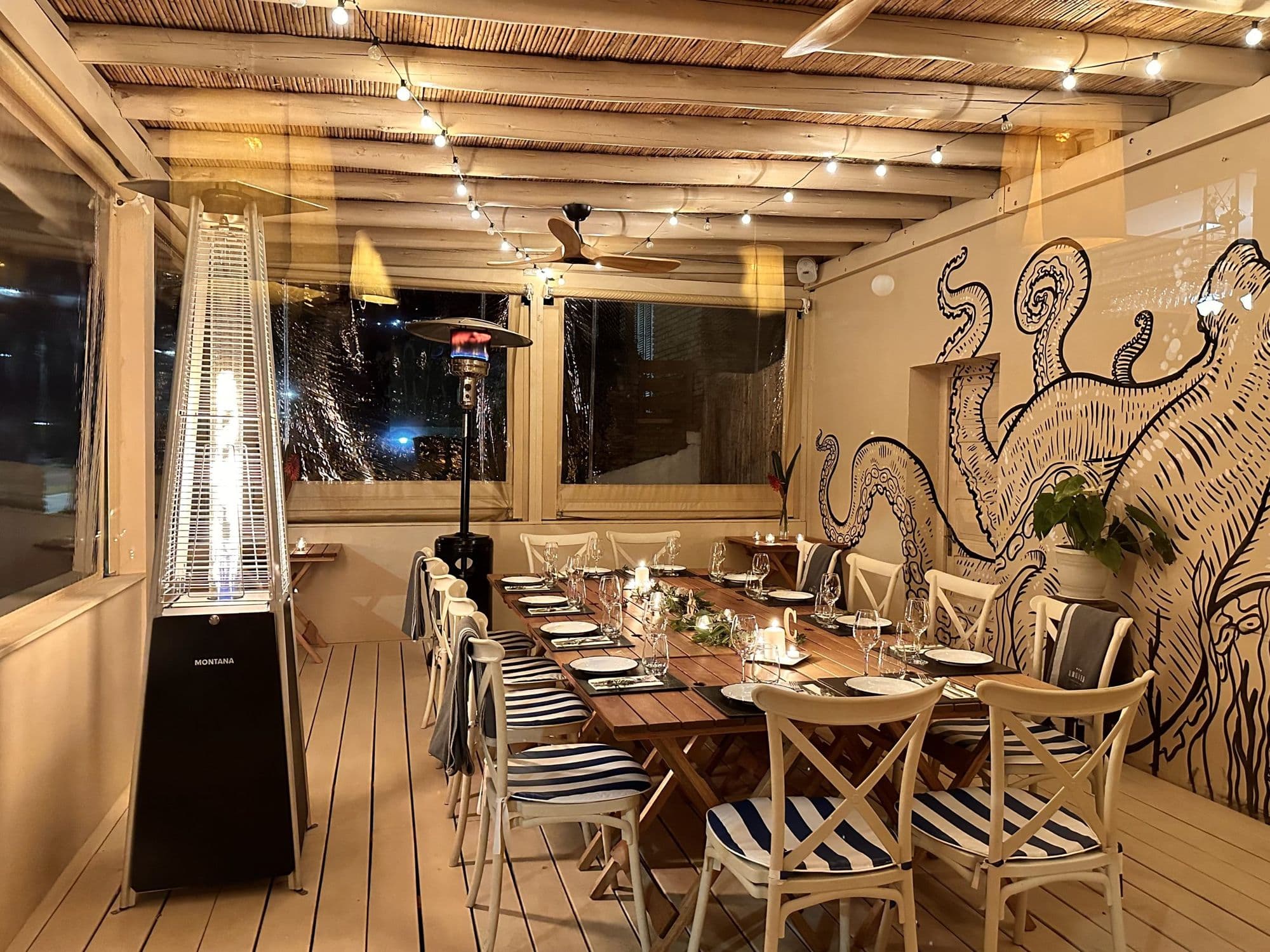 Salón de Kraken con mesa larga, sillas a rayas y un gran mural de pulpo