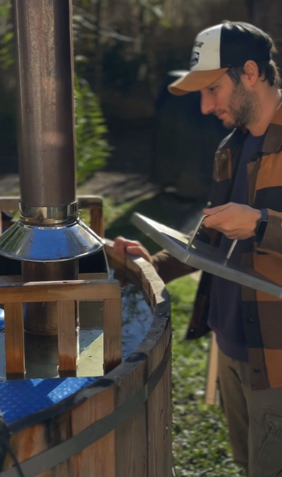 Alfo abriendo la tapa de la caldera de la tina, junto a la chimenea
