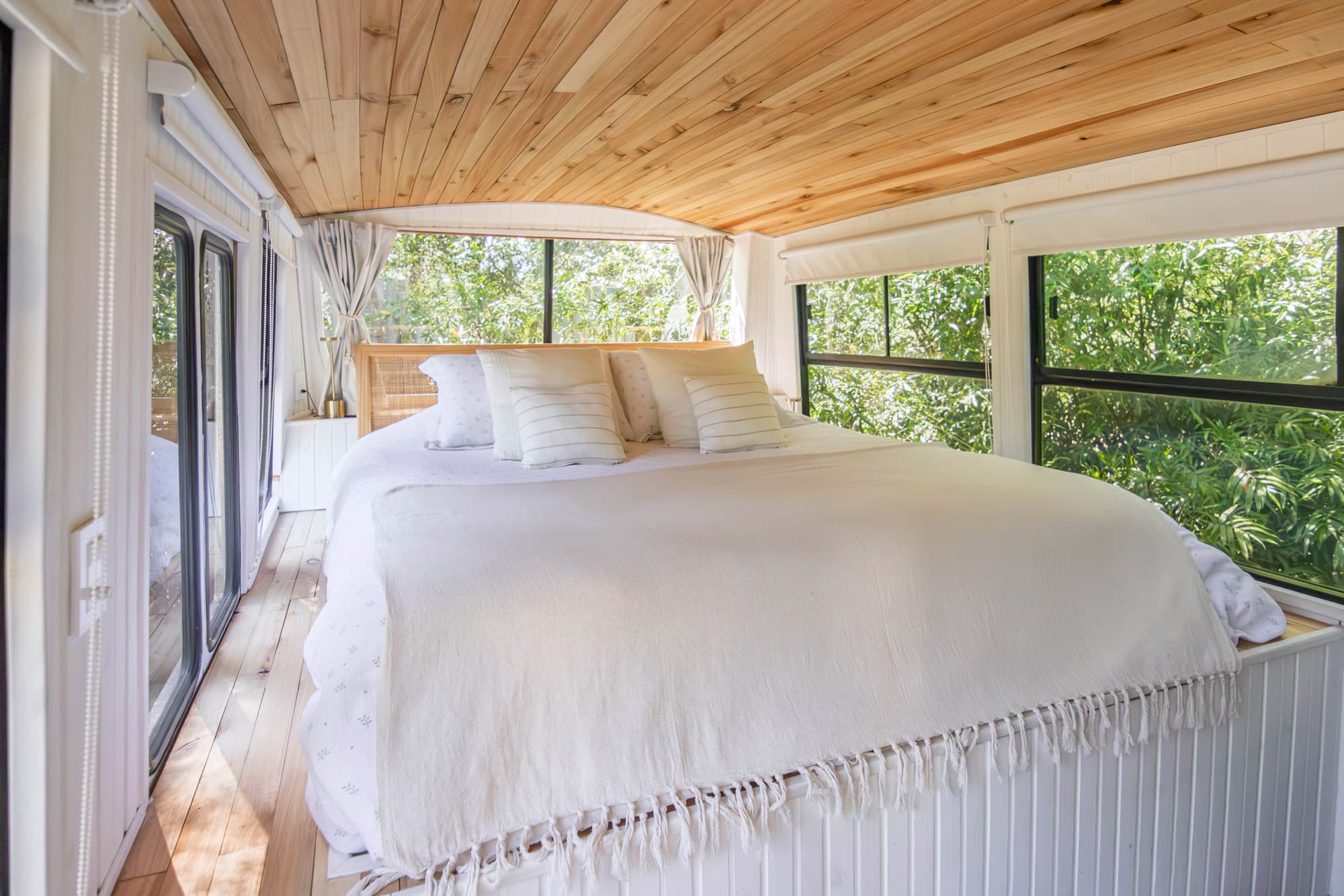 Dormitorio del BondiHouse — cama king size con ventanas panorámicas al bosque