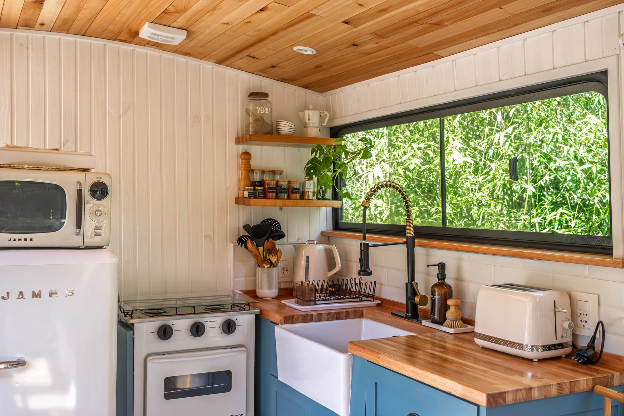 Cocina azul del BondiHouse — mesada de madera, heladera retro y ventana al jardín