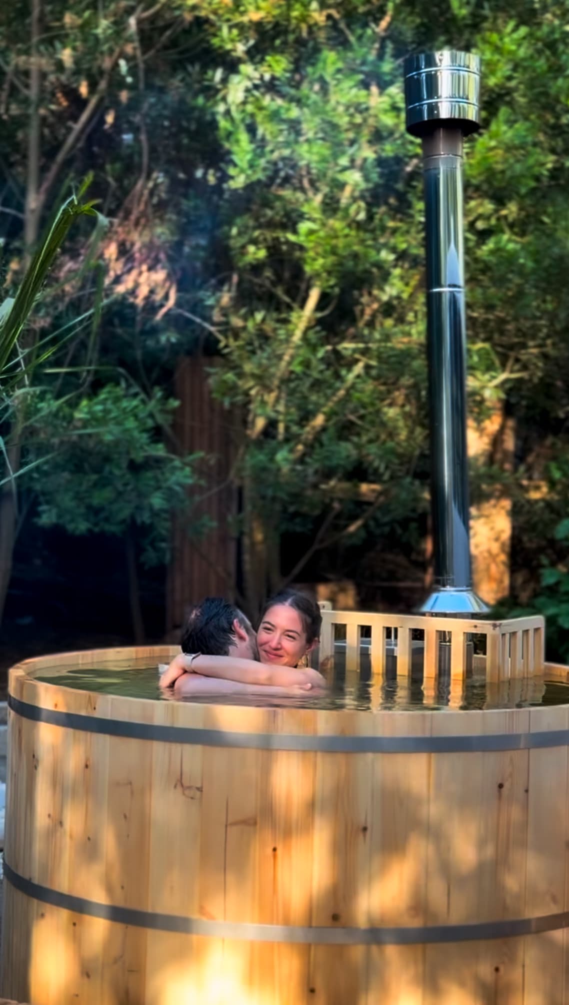 Tina de madera Onsen en el exterior de BondiHouse, rodeada de naturaleza